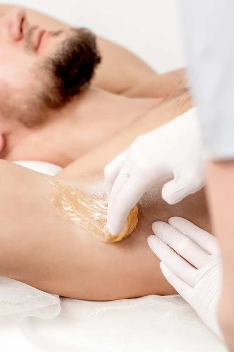 Profissional aplicando cera para depilação masculina
